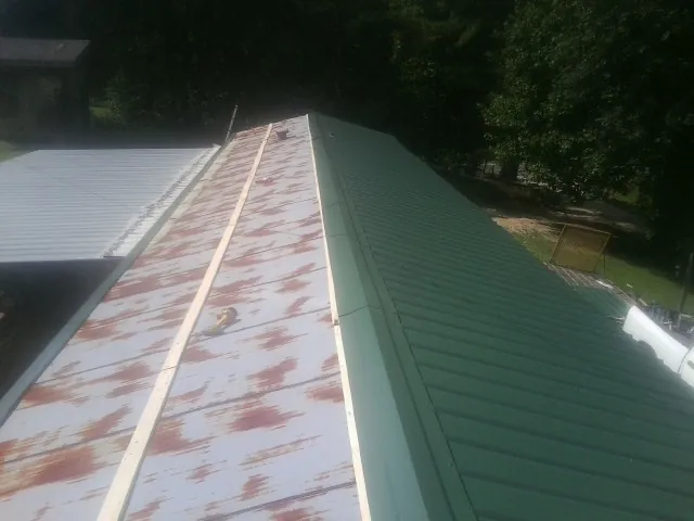 Old rusted panels beside newly installed green metal roofing — Wind Damage Roof Repair by Roofing Brothers in Ketchum