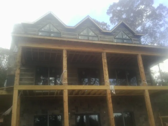 Dormers and porch framing on a large log home under construction — Roof Coating work by our crew in Ketchum