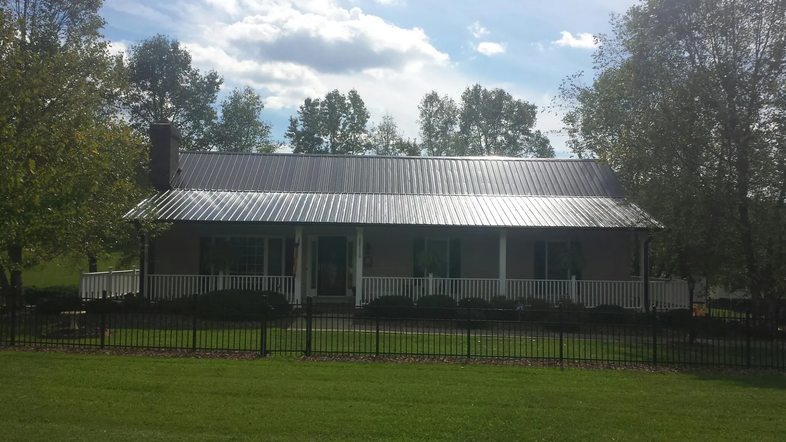 Gray metal roof on a brick ranch with a full width front porch — Gutter Guard Installation work by our crew in Ketchum