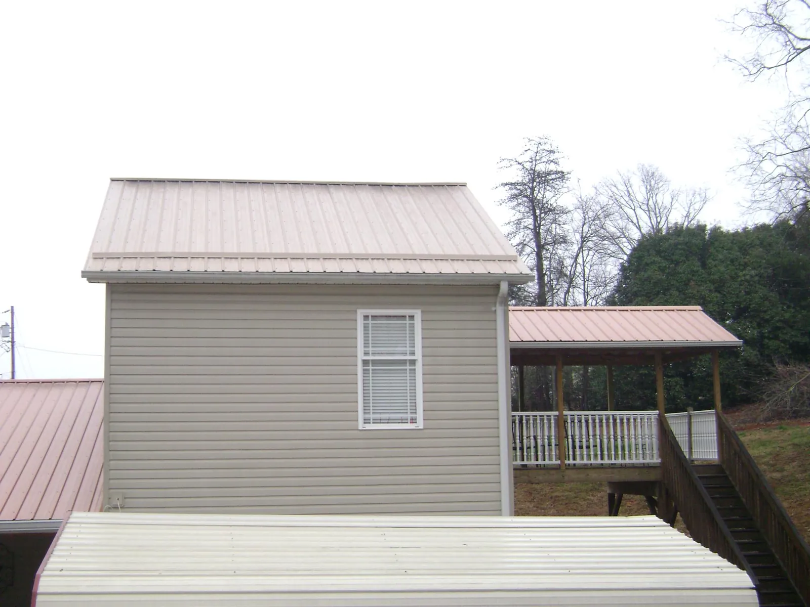 Tan metal roofs on a two story addition and attached porch, from a Roof Replacement job in Ketchum