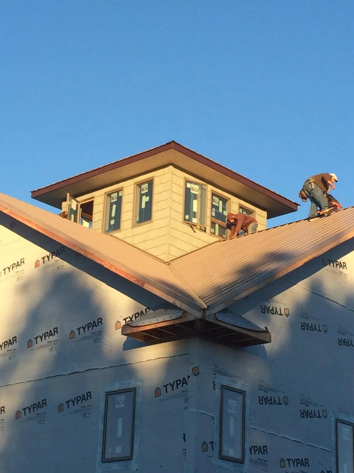 Roofers working around a rooftop cupola on a new metal roof at sunset — Roof Waterproofing in Ketchum by Roofing Brothers